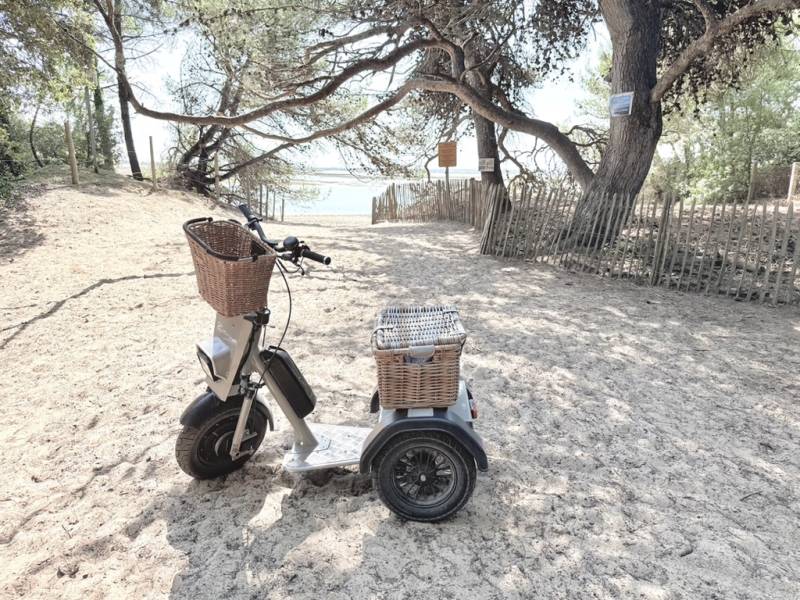 Trottinette électrique Lifestyle Cobrane avec paniers osier au bord de l'eau – tricycle trois roues pour location touristique et balades à La Rochelle et Île de Ré.