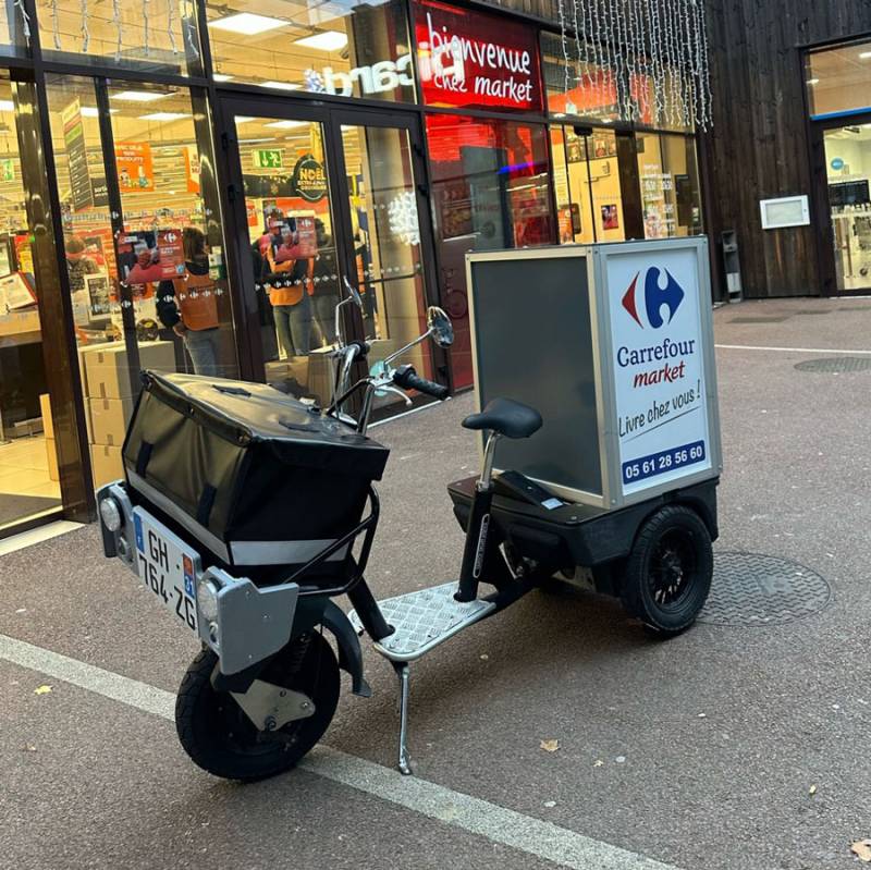 Triporteur électrique devant centre commercial Carrefour Market à Paris